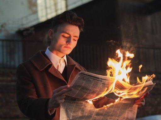 man reading burning newspaper