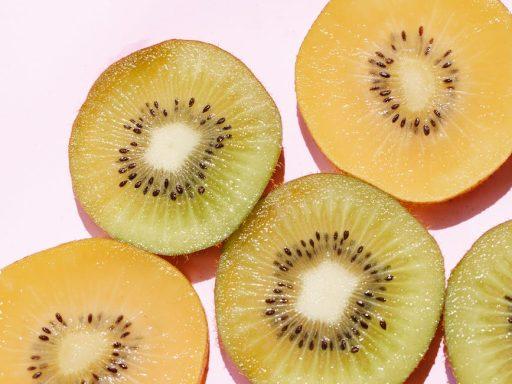 sliced assorted juicy kiwis on pink surface